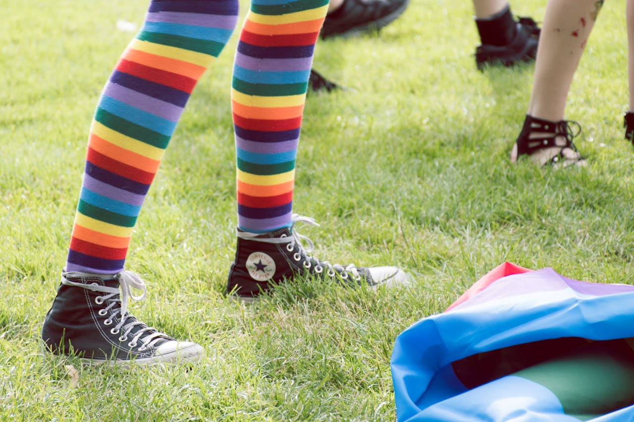 Rainbow-striped socks and sneakers at a vibrant outdoor pride celebration.