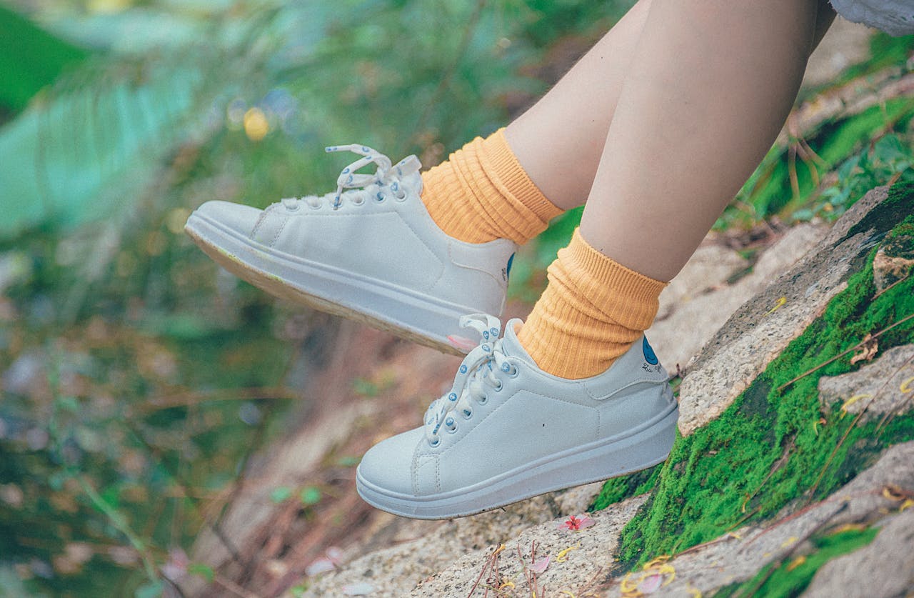 Casually dressed legs with sneakers and socks relaxing on a vibrant hillside.