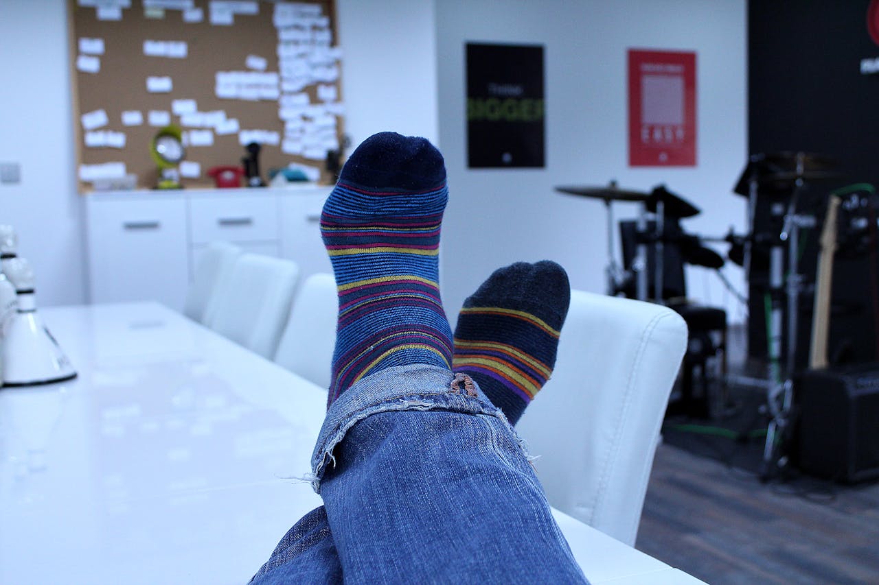 Relaxing in an office with colorful socks and blue jeans, showcasing casual comfort.