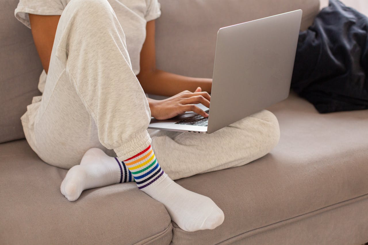 Person wearing rainbow socks while working on a laptop on the couch.